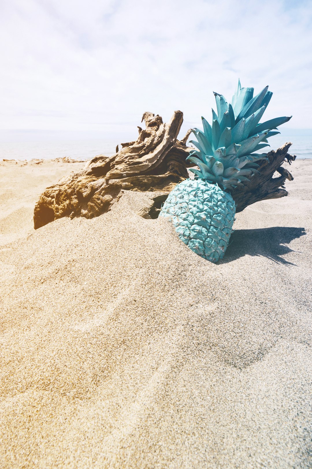 mint painted pineapple in sand at the beach