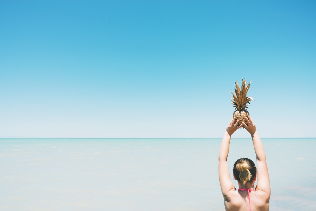 pineapple held up to sky by woman at beach