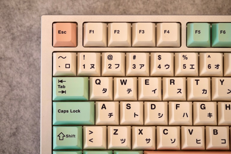 Mechanical keyboard with white, pastel green and red keycaps.